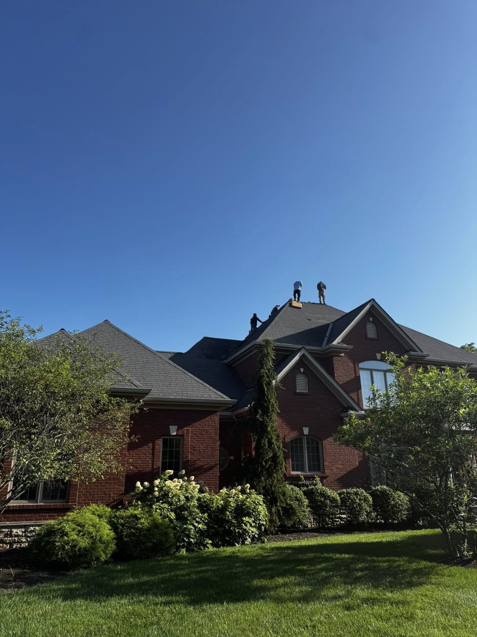 Roofing work underway on this brick home in Northern Kentucky. The crew is working across the steep roofline and multiple peaks.